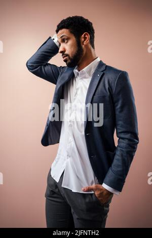Serious young businessman posing in studio over beige background. Stock Photo