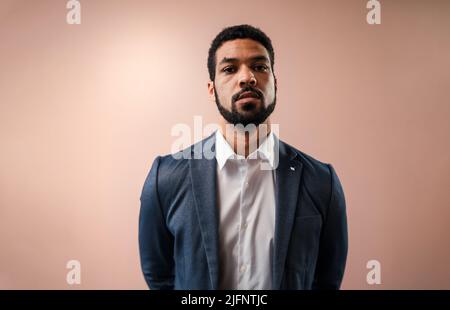 Serious young businessman looking at camera, studio shot. Stock Photo
