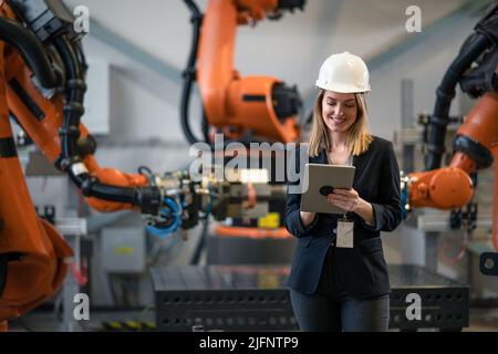 Portrait of female chief engineer in modern industrial factory using tablet. Stock Photo