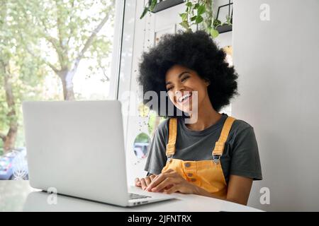 Smiling young woman sitting in cafe having video call using laptop. Stock Photo