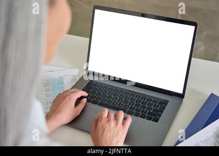 Female older businesswoman typing on laptop computer keyboard with empty screen. Stock Photo