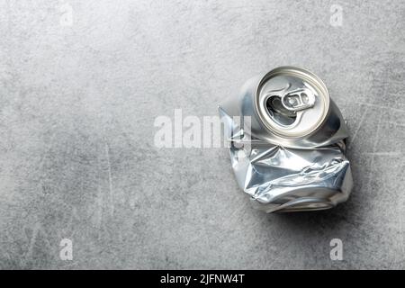 Empty crumpled can on a gray table. Top view. Stock Photo