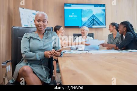 Confident, powerful african american businesswoman in a meeting with her colleagues holding a wireless tablet. Young business professional in her Stock Photo