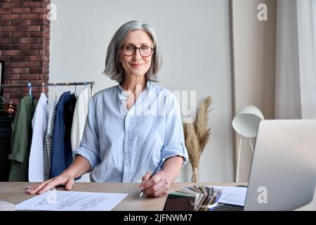 Portrait of mature fashion designer in showroom looking smiling in camera. Stock Photo