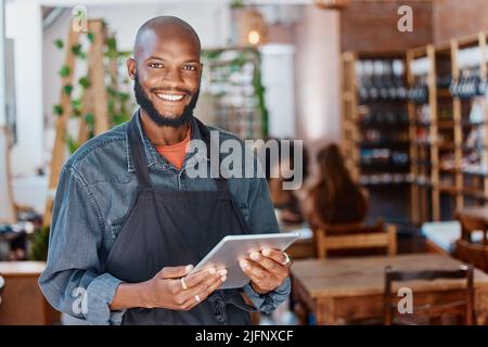 Young african american businessman working in a retail store using a digital tablet device. Portrait of a smiling small business owner, entrepreneur Stock Photo
