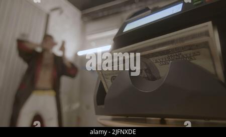 Machine that counts money and happy man. Footage. Rich man enjoys money. Man has received lot of money and is throwing it around Stock Photo