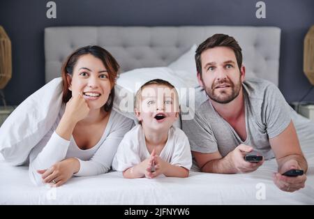 Glued to the tv for the day. Shot of a young family watching tv together at home. Stock Photo