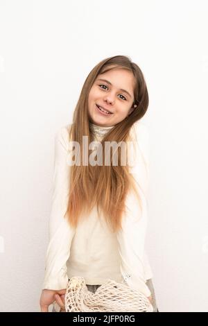 A cute beautiful girl shrugs her shoulders, expressing duality, the girl is shy to answer the question, a portrait, an isolated light background. Stock Photo