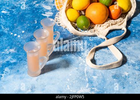 Ecological mesh bag with citrus fruits on a blue wooden background. Fresh produce in reusable cotton mesh bag . Zero waste concept ,mockup copy space. Stock Photo
