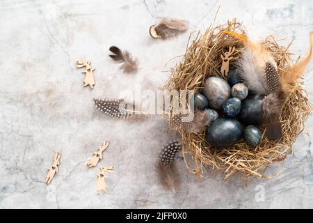 Marble blue Easter eggs in bird nest with feathers and copy space. Happy Easter holiday, top view, flat lay . Horizontal photo. Hibiscus eggs,  Stock Photo