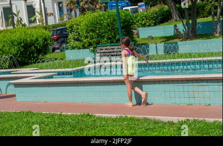 Cattolica Italy June 24 2022: Little girl playing and refreshes her hands with jets of water Stock Photo