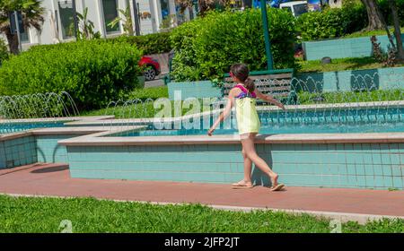 Cattolica Italy June 24 2022: Little girl playing and refreshes her hands with jets of water Stock Photo
