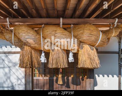 A sacred rice straw rope (shimenawa) marks the entrance to a Shinto ...