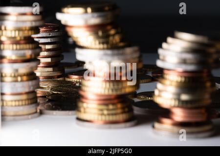 Stacked Euros leaning to the right. Euro coins in different sizes and denominations. Coins in the background in focus Stock Photo