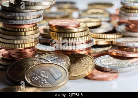 Bunch of Euro coins, stacked coins on white surface. Different coins all over the place Stock Photo