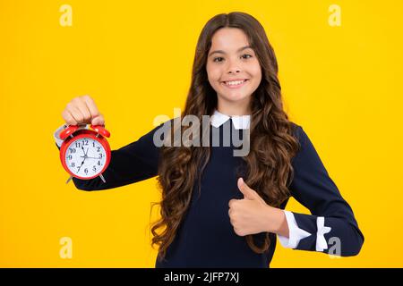Teen girl 12, 13, 14 years old look at alarm clock. Time for shopping sales. Good morning, checking time. Stock Photo