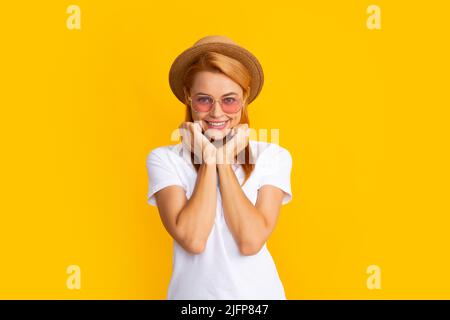 Smiling portrait of pretty young woman wearing sunglasses and straw hat over yellow background. Happy girl enjoying summer. Stock Photo