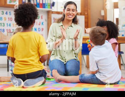 Sing and be happy. Shot of a teacher singing with her preschool children. Stock Photo