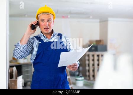 Portrait of foreman holding documentation and talking on phone Stock Photo