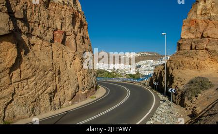 The road leading through the volcanic mountains to the village and beach of Puerto Rico in Gran Canaria, Spain Stock Photo