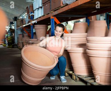 Young woman customer choosing big clay pot for garden Stock Photo