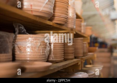 Clay plates for flower pots in stretch film on shelves in store Stock Photo