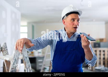 Foreman using smartphone, recording voice message Stock Photo