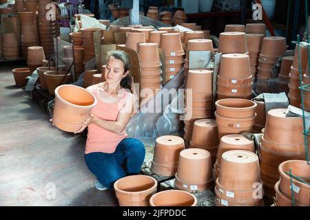 Female seller is standing near clay pots in stock Stock Photo