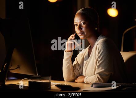 Focused on getting done and dusted with her deadline. Shot of a young businesswoman talking on a cellphone while working on a computer in an office at Stock Photo