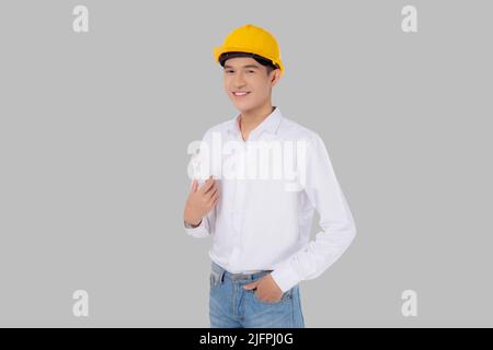 Portrait young asian man is engineer wearing helmet standing and holding blueprint with confident isolated on white background, handsome male is archi Stock Photo