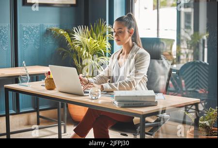 Focused on my end goal. Shot of a young businesswoman using a laptop in an office. Stock Photo