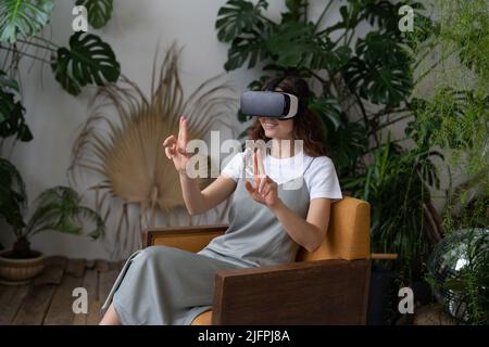 Curious woman in virtual reality glasses interacting with objects in interactive immersive world Stock Photo