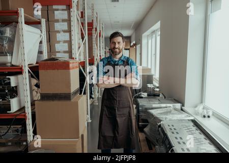 Portrait of rman in uniform standing on workshop of coffee machines warehouse Stock Photo