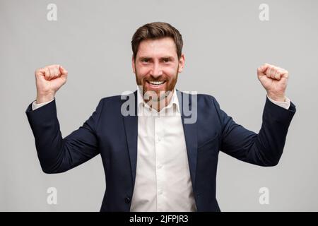 Happy joyful businessman wearing suit doing winner gesture clenching fists  Stock Photo