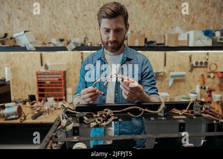 Smiling young worker repairing coffee machine in a workshop Stock Photo