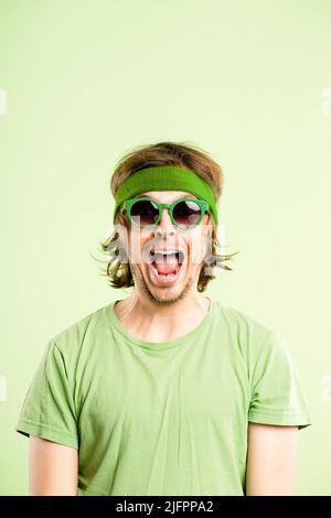 Im so excited for you. Shot of a handsome young man standing alone in the studio and looking excited while wearing a headband. Stock Photo