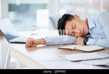 Sleeping so I can be productive later. Shot of a young businessman sleeping at his desk in an office. Stock Photo