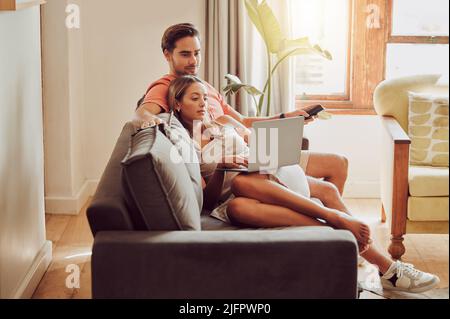 Home is wherever we are together. Shot of a young couple using a laptop together at home. Stock Photo