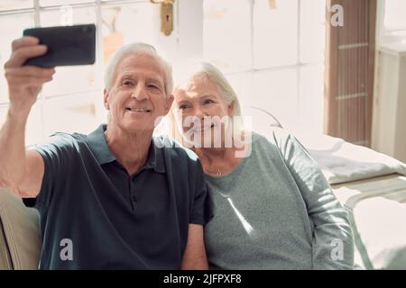 One more for the road. Cropped shot of an affectionate senior couple sitting in their living room at home. Stock Photo