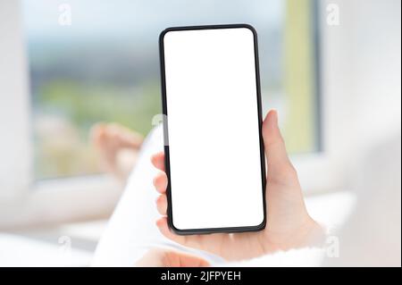 woman user customer hold cellphone mockup with white screen in hand. Use mobile shopping app, check social media news, texting mobile sms order food d Stock Photo