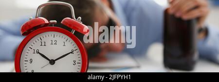 Red vintage clock show time, drunk man fell asleep on workplace in office Stock Photo