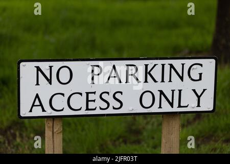 White road sign with the words No parking, access only in front of a green background Stock Photo
