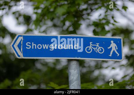 Blue road sign saying showground and pictograms of bicycle, pedestrian and arrow Stock Photo