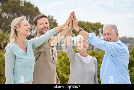 Rejoice with your family in the beautiful land. Shot of a family giving each other a high five in the garden at home. Stock Photo
