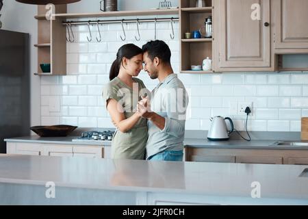 Lets make the most of this moment. Shot of a young couple dancing in the kitchen at home. Stock Photo