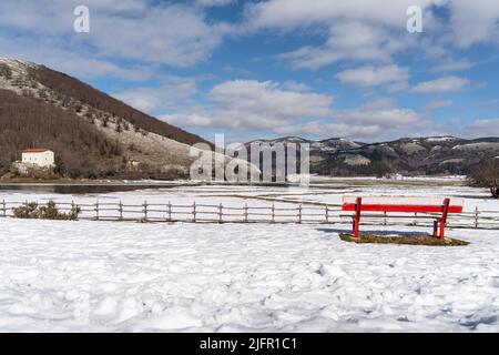 Red bench facing Laceno Lake landscape during winter, Bagnoli Irpino, Campania, Italy Stock Photo
