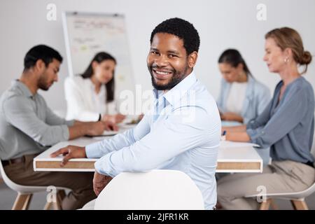 Its great to be a part of these meetings. Cropped portrait of a handsome young businessman sitting in the boardroom during a meeting with her Stock Photo