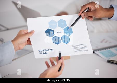 Looking over the data. High angle shot of a group of unrecognizable businesspeople looking over paperwork in the boardroom. Stock Photo