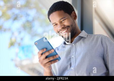 Keeping up with connections. Low angle shot of a young businessman using a cellphone in an office. Stock Photo
