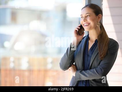 That sounds lovely to me. Shot of a young businesswoman talking on a cellphone in an office. Stock Photo